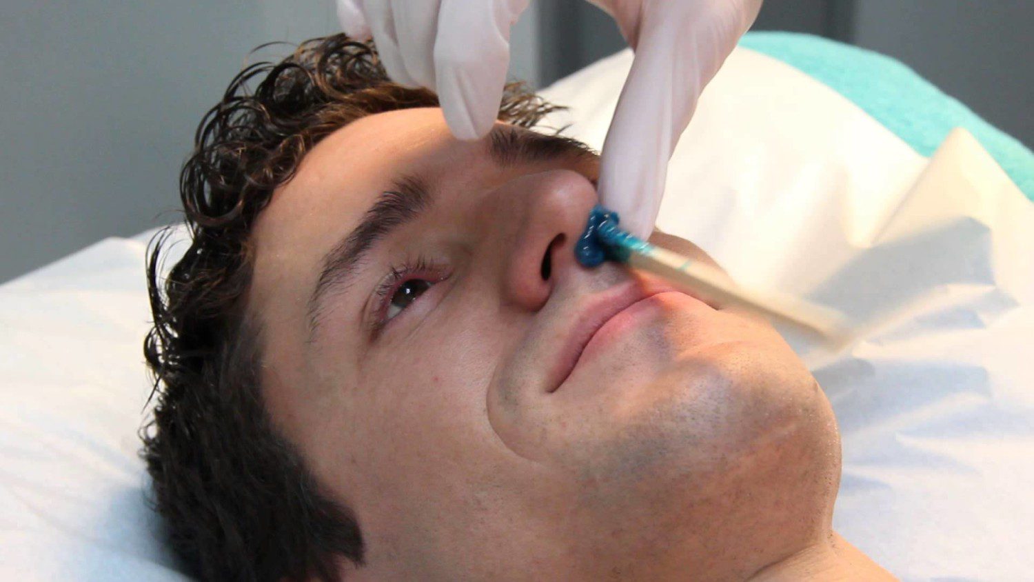 A man is getting his nose cleaned by someone.