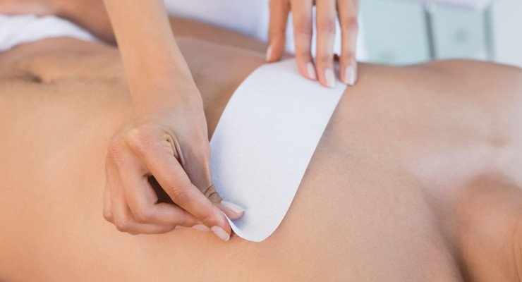 A person is waxing their back with white paper.