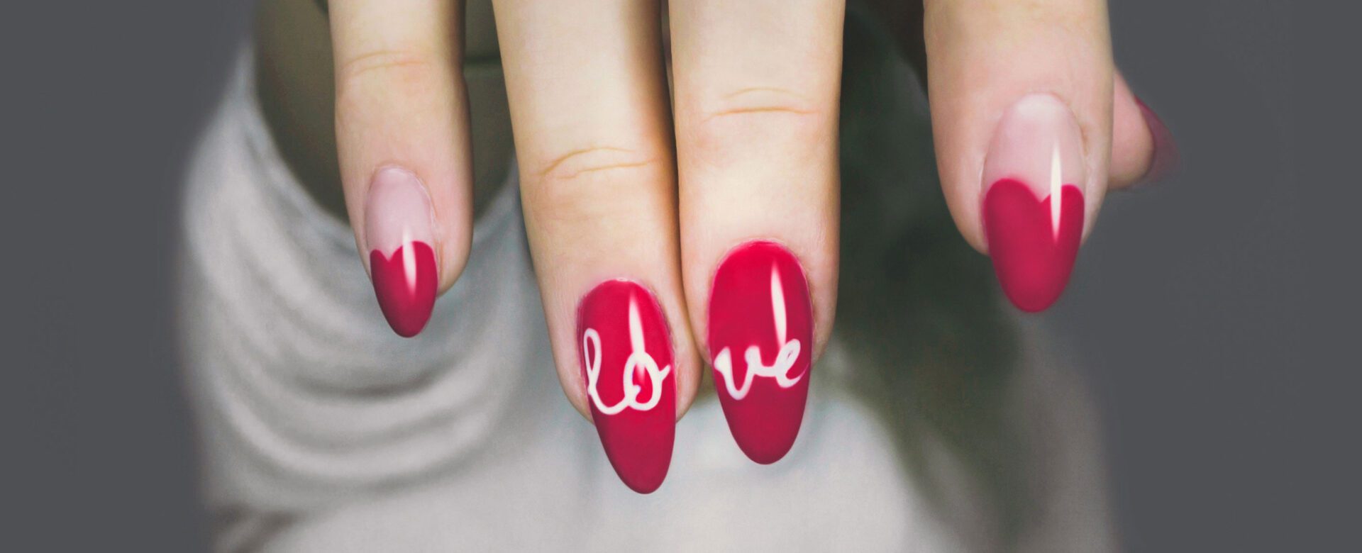 A woman with red nails and white writing on them.