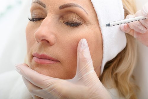 A woman getting her face waxed by an esthetician.