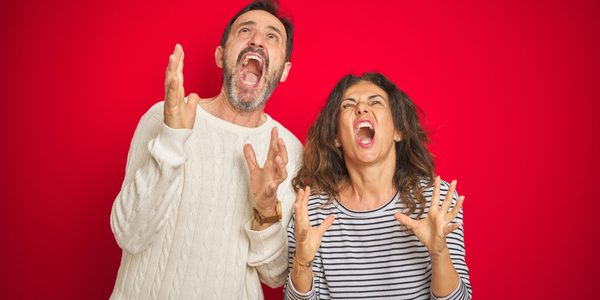 A man and woman are standing up with their hands in the air.