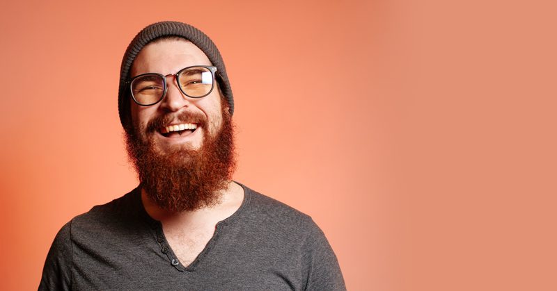 A man with a beard and glasses smiling.