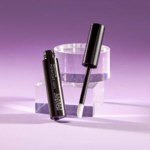 A black and white bottle of mascara next to a clear container.